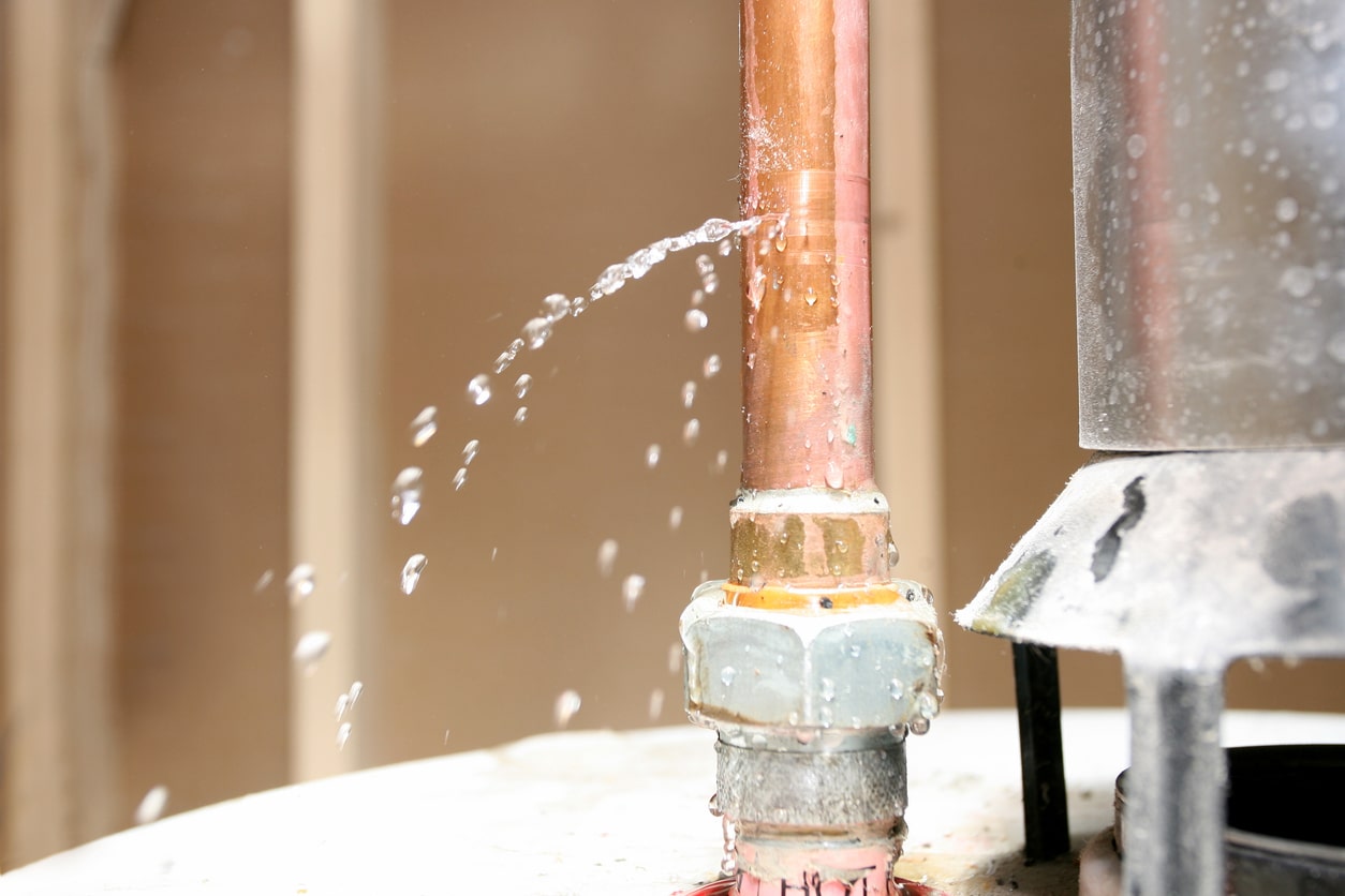 A close-up image of a pipe leaking water from the top of a water heater.